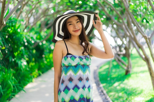 Glimlach van de portret de mooie jonge Aziatische vrouw en gelukkige rond openluchttuin