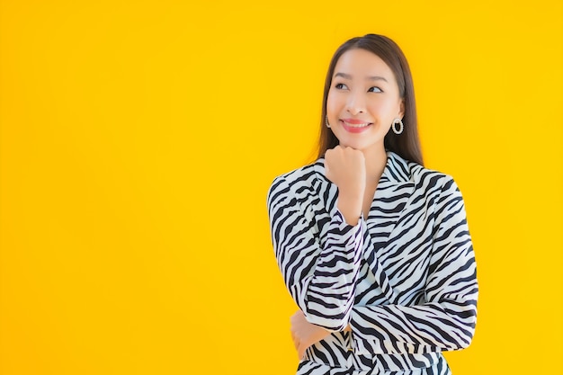 Glimlach van de portret de mooie jonge Aziatische vrouw gelukkig met actie betreffende geel