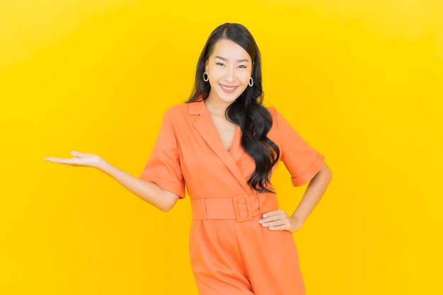 Glimlach van de portret de mooie jonge Aziatische vrouw met actie op geel