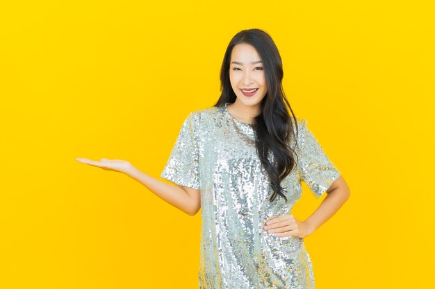 Glimlach van de portret de mooie jonge Aziatische vrouw met actie op geel