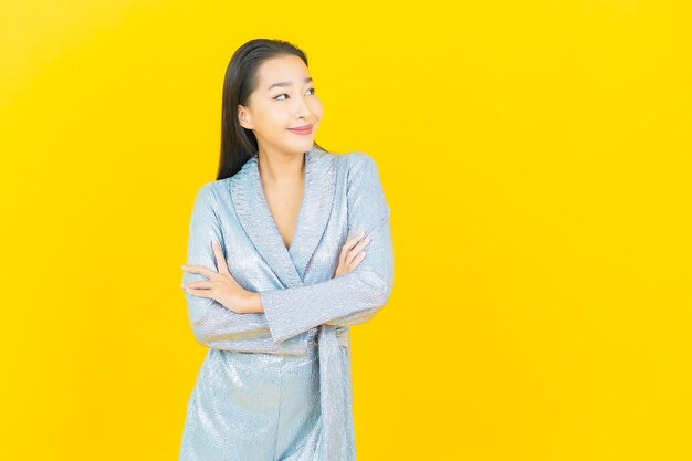 Glimlach van de portret de mooie jonge aziatische vrouw met actie op gele muur