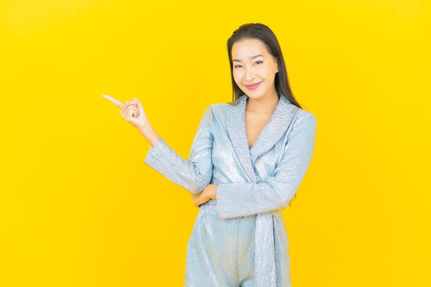 Glimlach van de portret de mooie jonge aziatische vrouw met actie op gele muur
