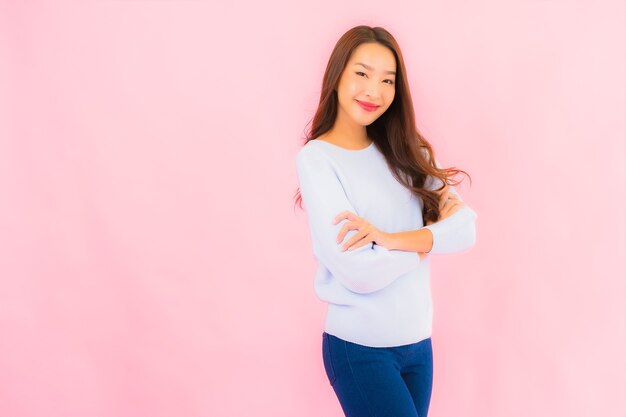 Glimlach van de portret de mooie jonge Aziatische vrouw met actie op roze geïsoleerde muur