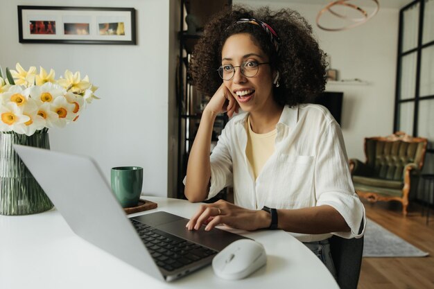 Glimlach vrouw die thuis zit en naar laptop kijkt