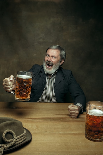 Glimlachend bebaarde man bier drinken in pub