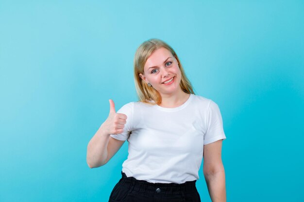 Glimlachend blond meisje vertoont perfect gebaar op blauwe achtergrond