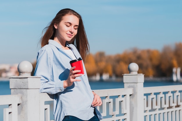 Glimlachend blondemeisje die een kop van koffie houden