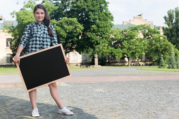 Glimlachend highschool meisje bedrijf schoolbord