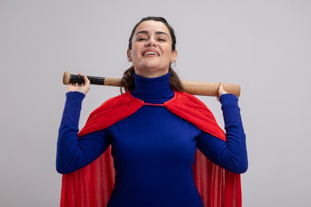 Glimlachend jong die de holdingshonkbalknuppel van het superheromeisje achter hals op wit wordt geïsoleerd