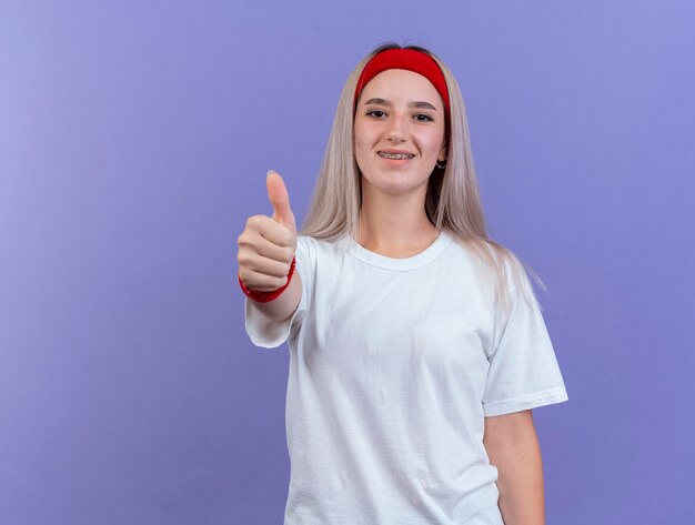 Glimlachend jong Kaukasisch sportief meisje met steunen die hoofdband dragen