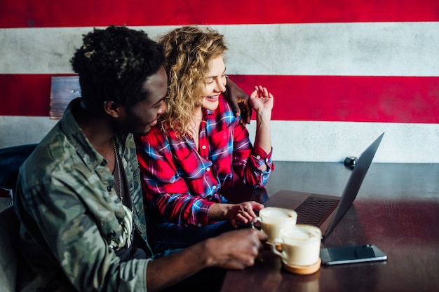 Glimlachend jong koppel in een coffeeshop met behulp van touchscreen computer. Jonge man en vrouw in een restaurant kijken naar digitale tablet.