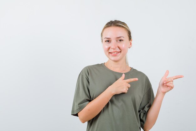 Glimlachend jong meisje dat rechts met vingers op witte achtergrond toont