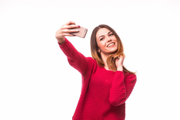 Glimlachend jong meisje dat selfiefoto op smartphone maakt die over grijze muur wordt geïsoleerd