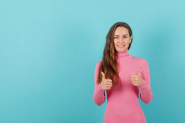 Glimlachend jong meisje vertoont perfecte gebaren met duimen op blauwe achtergrond