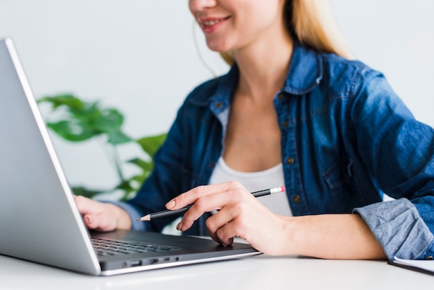 Glimlachend jong wijfje die laptop in werkplaats met behulp van