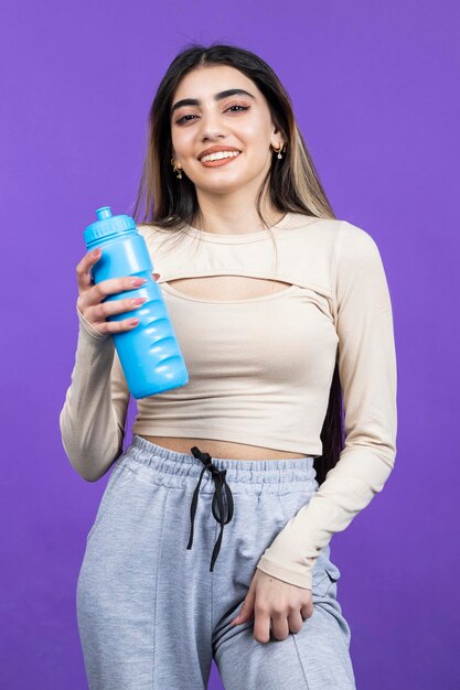 Glimlachend meisje dat blauwe waterfles vasthoudt en lacht Foto van hoge kwaliteit