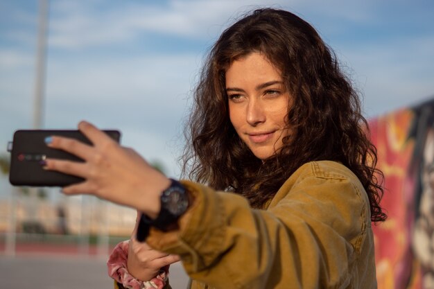 Glimlachend meisje dat een selfie neemt in een skatepark tijdens het gouden uur