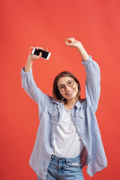 Glimlachend meisje in vrijetijdskleding en oortelefoons dansende bewegende handen.