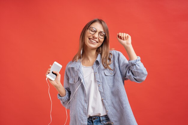 Glimlachend meisje in vrijetijdskleding en oortelefoons dansende bewegende handen.