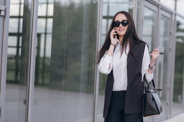 Glimlachend meisje met een zonnebril praten over haar telefoon