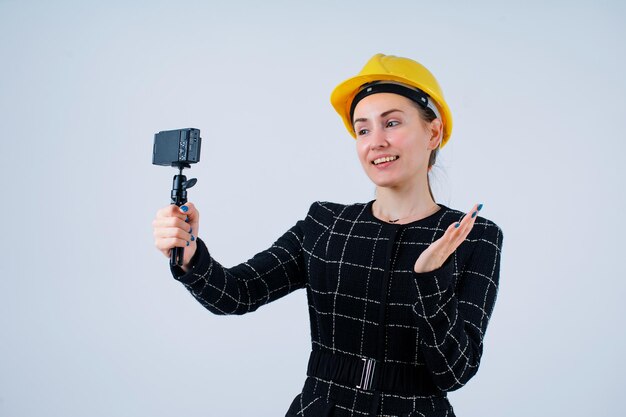 Glimlachend meisje neemt selfie met haar camera door haar hand op te steken op een witte achtergrond