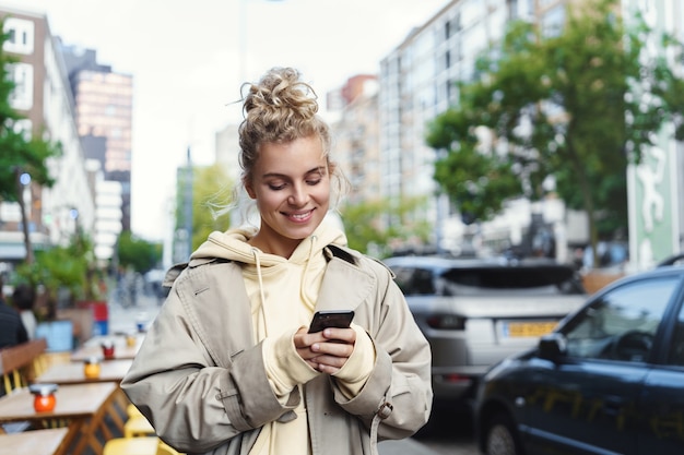 Gratis foto glimlachend mooi blond meisje dat mobiele telefoon met behulp van.