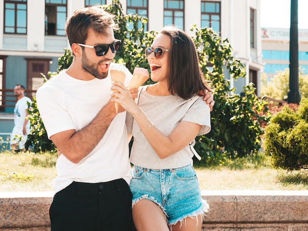 Glimlachend mooie vrouw en haar knappe vriendje vrouw in casual zomerkleren gelukkige vrolijke familie paar poseren op de straat achtergrond in zonnebril lekker ijs eten in wafels kegel