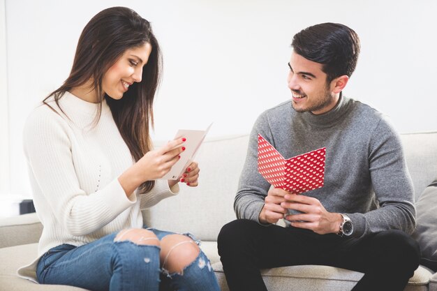 Glimlachend paar te kijken naar ansichtkaarten met een hart