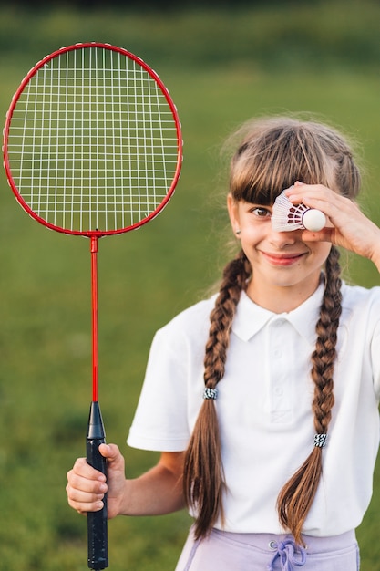 Glimlachend portret van een badminton van de meisjesholding en een shuttle over haar ogen