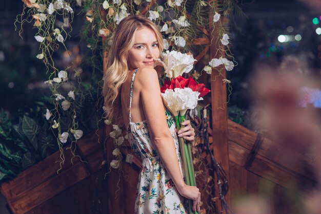 Glimlachend portret van een blonde jonge vrouw met bloemen in de hand