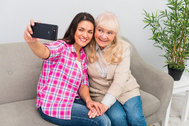 Glimlachend portret van een hogere vrouw en een moeder die selfie op mobiele telefoon nemen