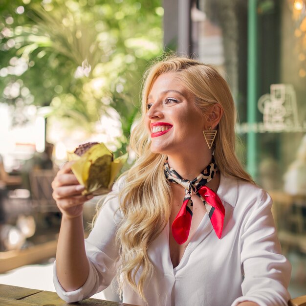 Glimlachend portret van een jonge muffin die van de vrouwenholding in hand weg kijken