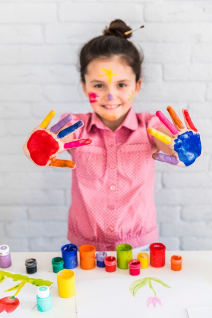 Glimlachend portret van een meisje die haar geschilderde kleurrijke hand tonen