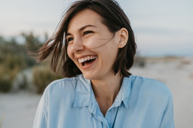 Glimlachend portret van spontane lachende vrouw op het strand