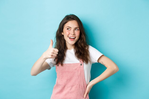 Glimlachend schattig tienermeisje met mooie blos en glamour make-up met duim omhoog in goedkeuring, kijk naar