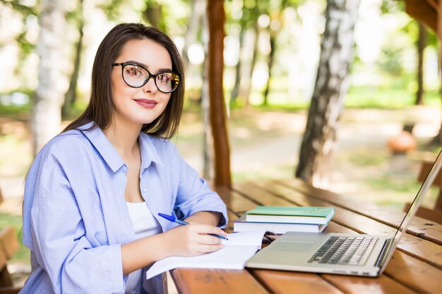 Glimlachend studentenmeisje dat aan het eind van de dag laptop in een parklijst met behulp van