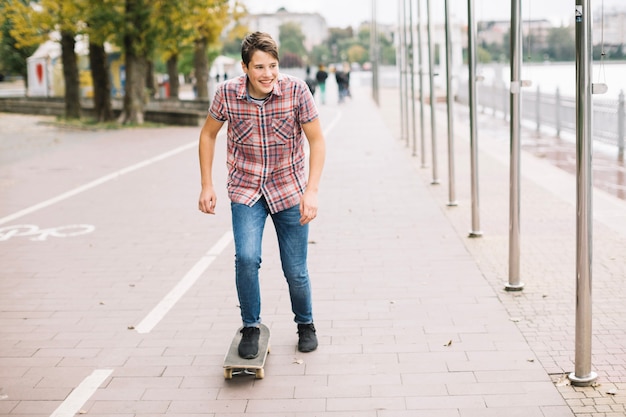 Glimlachend tiener berijdend skateboard dichtbij fietssteeg