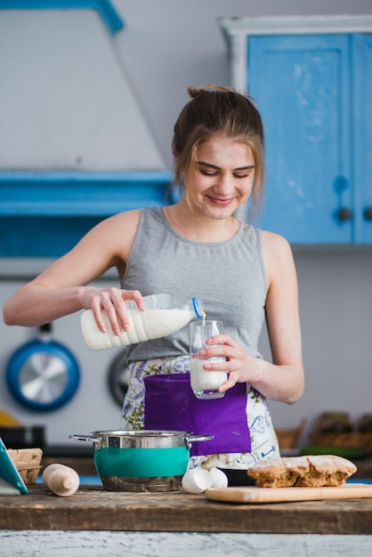 Glimlachend vrouwen vullend glas met melk