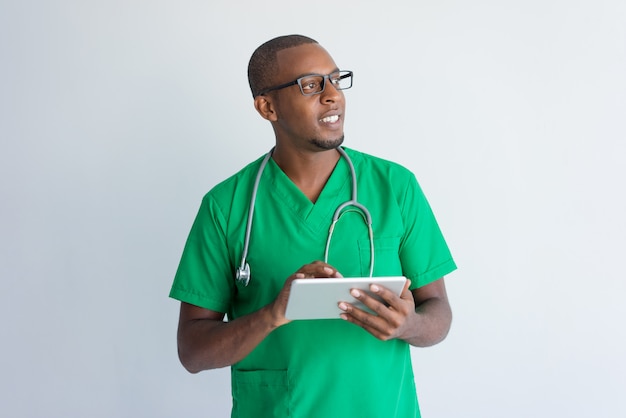 Glimlachende Afrikaanse Amerikaanse arts die digitale tablet gebruikt.