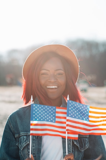 Gratis foto glimlachende afrikaanse amerikaanse vrouw met amerikaanse vlaggen