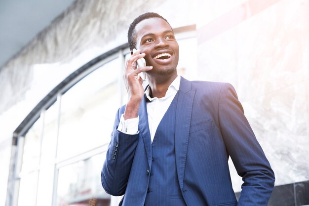 Glimlachende Afrikaanse jonge zakenman die op mobiele telefoon spreekt