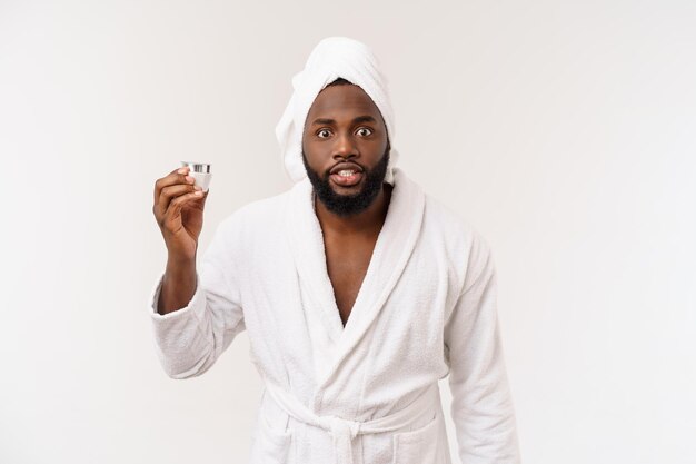 Glimlachende Afro-Amerikaanse man die crème op zijn gezicht aanbrengt Man's skin care concept