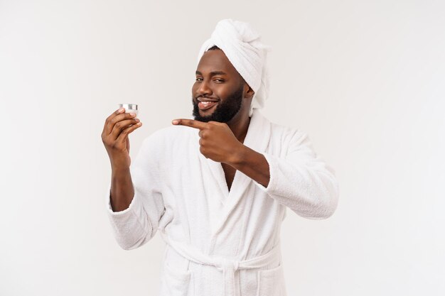 Glimlachende Afro-Amerikaanse man die crème op zijn gezicht aanbrengt Man's skin care concept