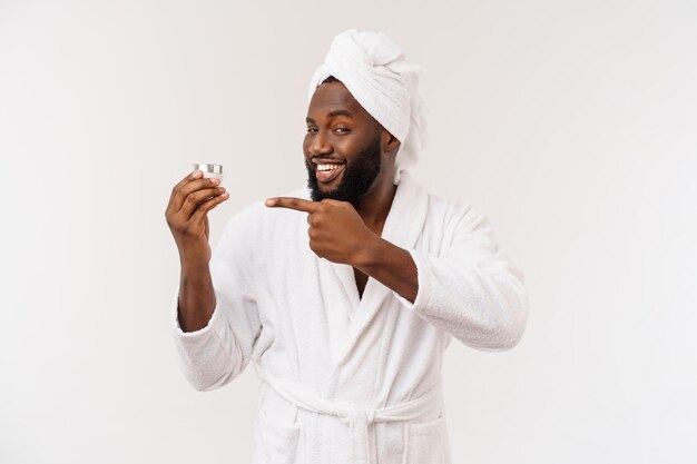 Glimlachende Afro-Amerikaanse man die crème op zijn gezicht aanbrengt Man's skin care concept