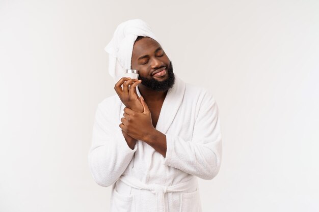 Glimlachende afro-amerikaanse man die crème op zijn gezicht aanbrengt man's skin care concept