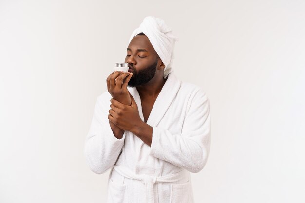 Glimlachende Afro-Amerikaanse man die crème op zijn gezicht aanbrengt Man's skin care concept