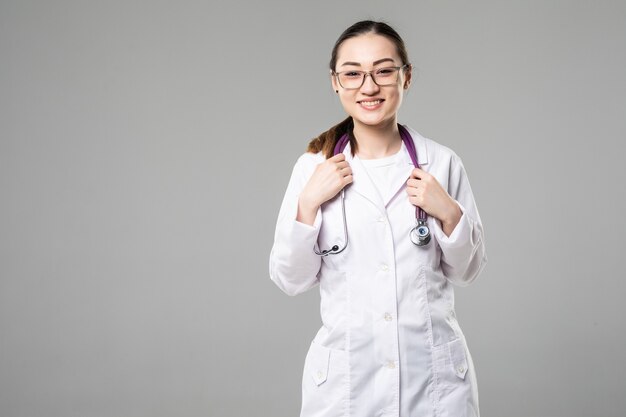 Glimlachende arts aziatische vrouw met gekruiste armen tegen witte muur