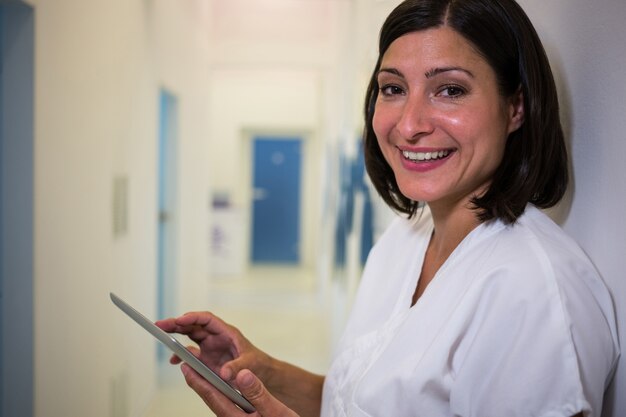 Glimlachende arts die digitale tablet gebruiken bij kliniek