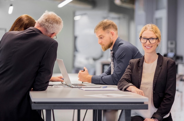 Gratis foto glimlachende bedrijfsvrouw voor haar collega die op het werk werkt