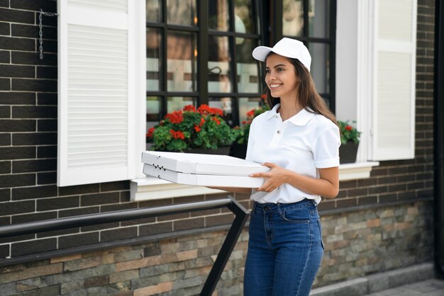 Glimlachende bezorger die dozen pizza draagt